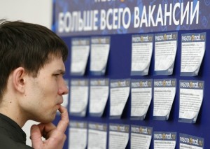 робота вакансия A man reads job offers posted at a job fair in Moscow